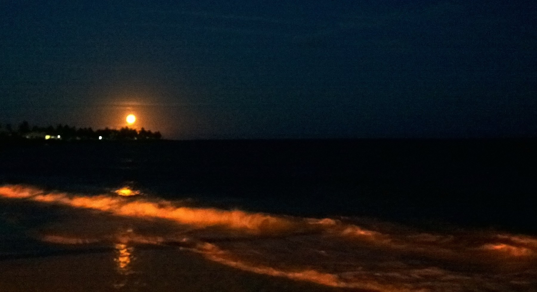Anoitecer na Praia do Saco, com ondas, reflexos na água e a faixa de areia em tons escuros